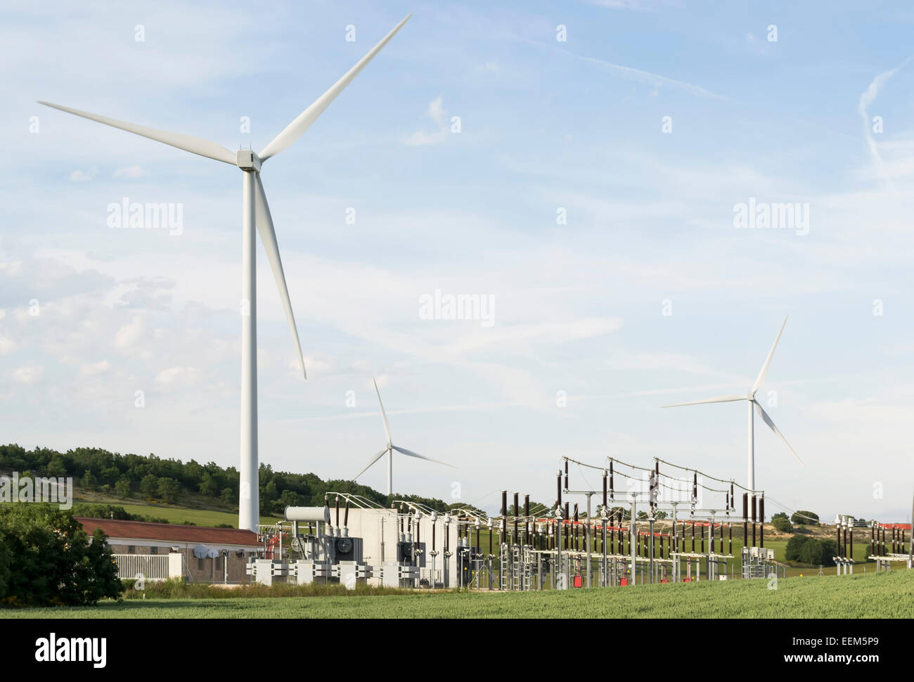 Windpark Turbinen mit nahe gelegenen elektrische Kraftwerk für die Verteilung der geernteten Energie Stockfoto