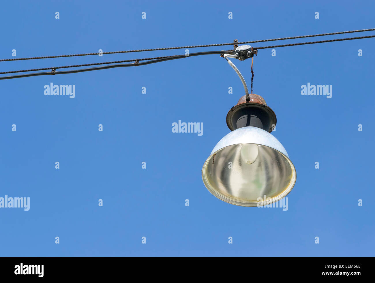 Vintage Straße Lichtkegel mit Glühbirne hängen von einem Stahlseil auf einem tiefblauen Himmel Stockfoto