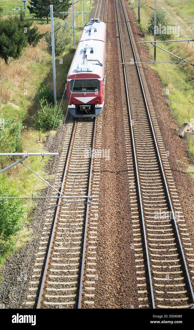 Luftaufnahme von einem ankommenden Zug mit zwei Pkw auf einer elektrifizierten Bahnstrecke Stockfoto