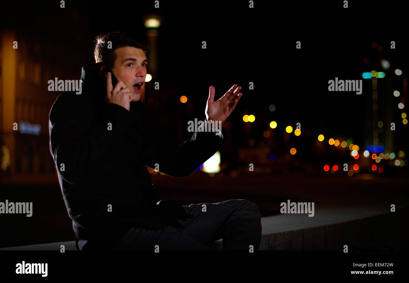 Deutschland, Berlin, Porträt des jungen Mannes telefonieren auf Straße in der Nacht Stockfoto
