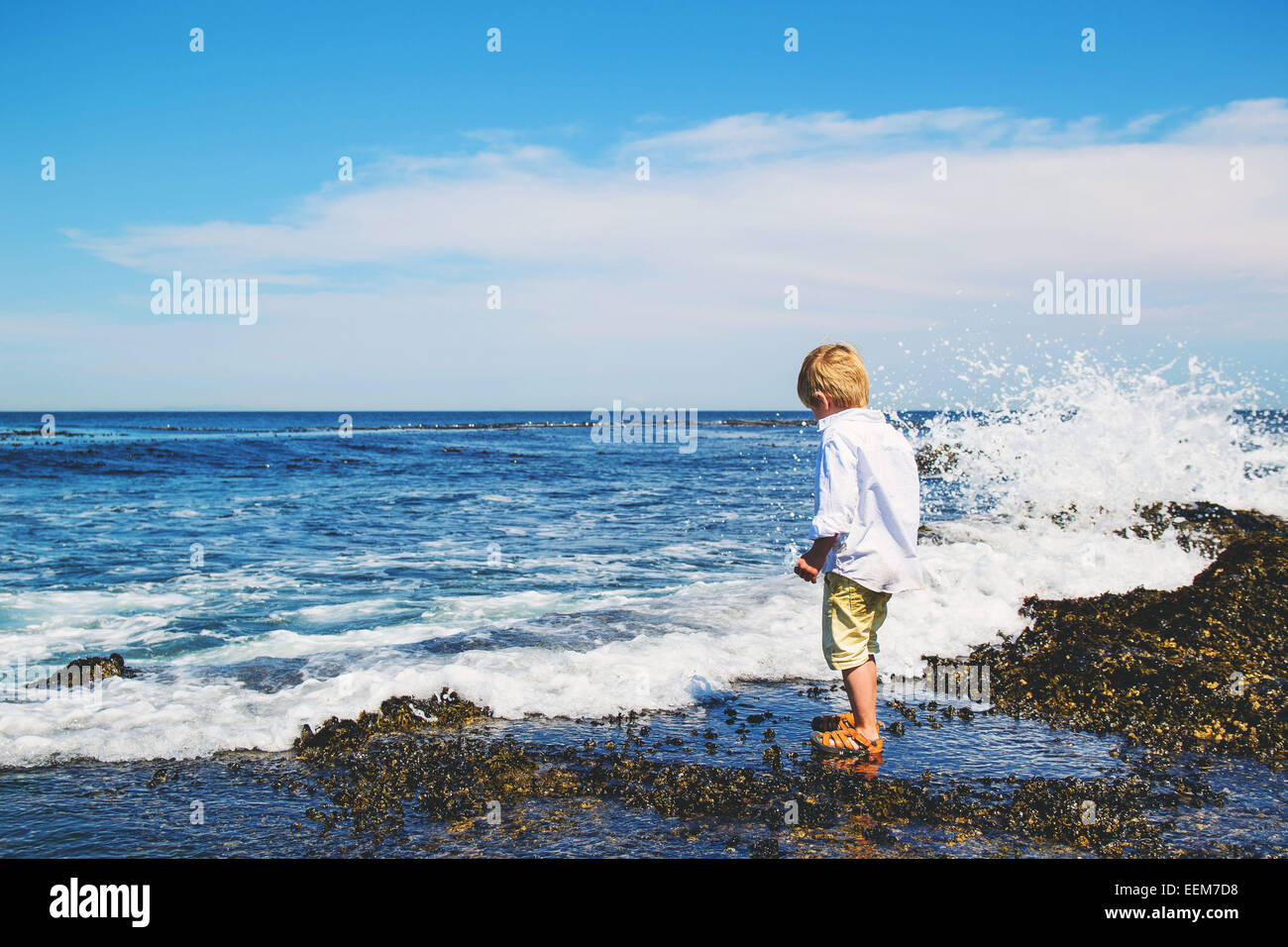 Junge auf nassen Felsen am Meer Stockfoto