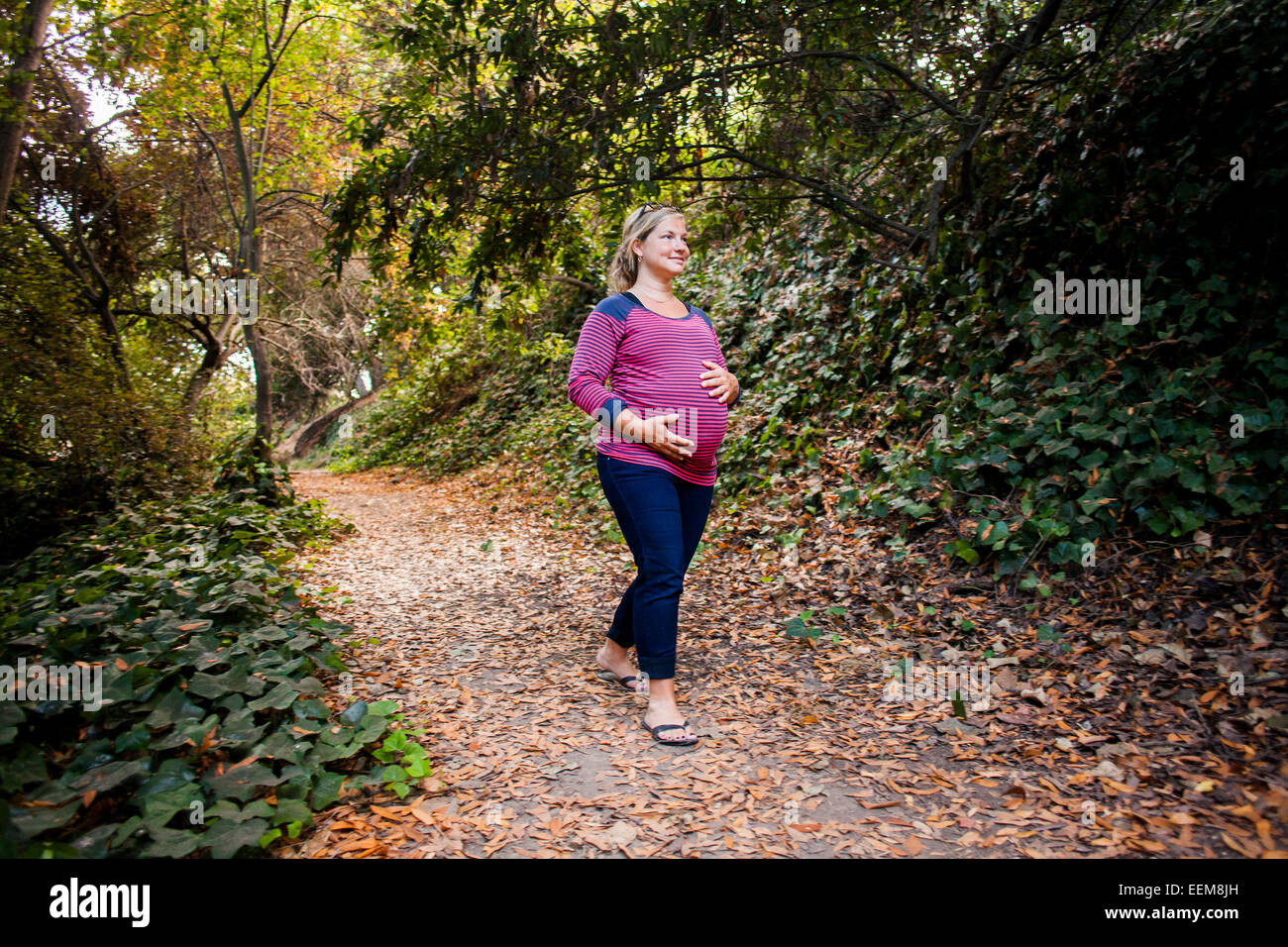 Schwangere Frau kaukasischen Waldweg den Bauch festhalten Stockfoto