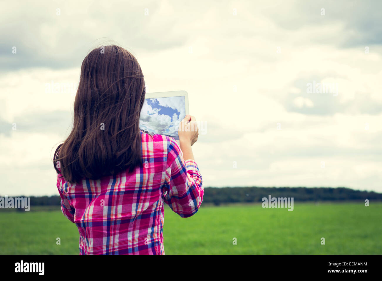 Kaukasische Mädchen nehmen Foto mit Tablet-PC auf Wiese Stockfoto