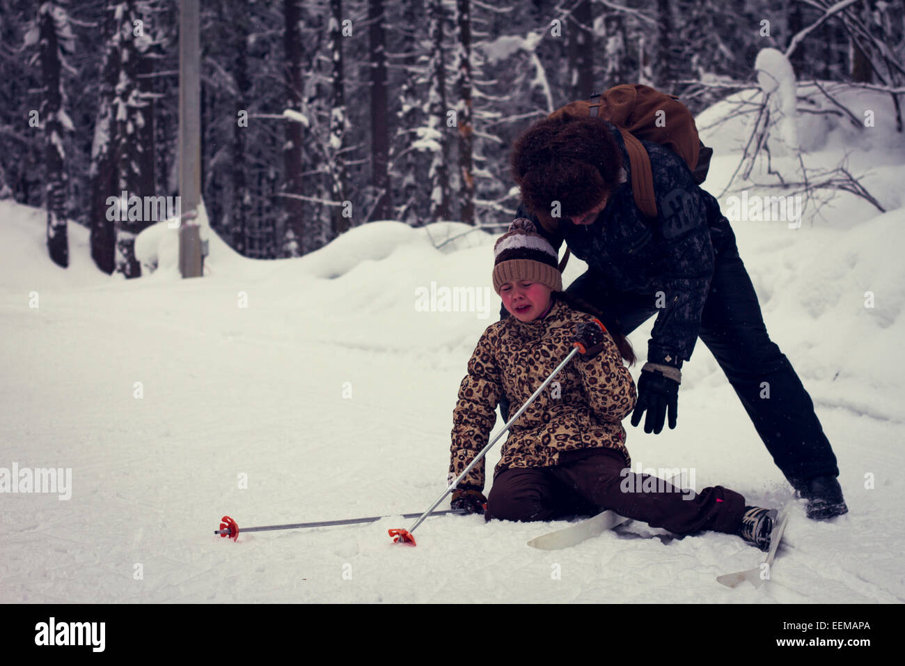 Kaukasische Vater helfen Langlauf Tochter fallen im Schnee Stockfoto