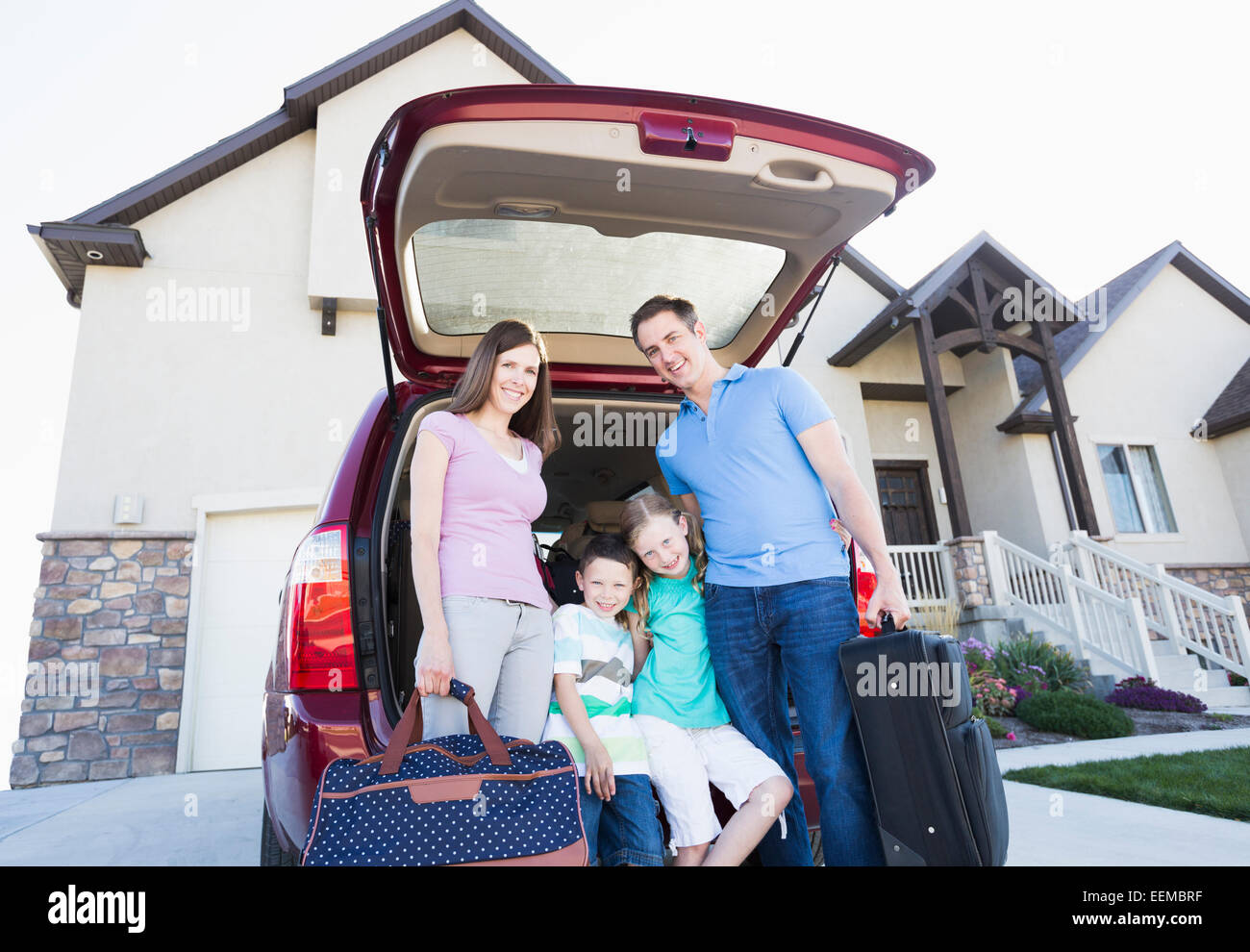 Kaukasische Familienholding Koffer mit dem Auto Stockfoto