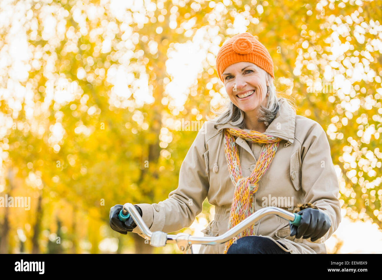 Ältere kaukasischen Frau Reiten Fahrrad unter Herbst Bäume Stockfoto
