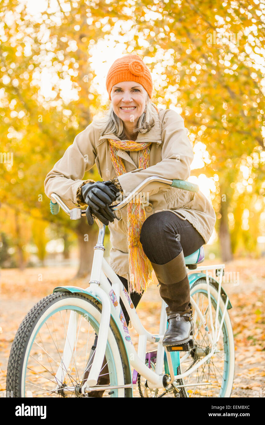 Ältere kaukasischen Frau Reiten Fahrrad auf Herbst Blätter Stockfoto