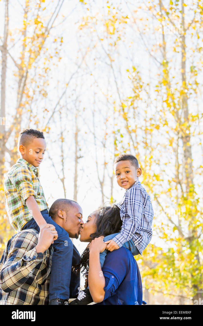 Eltern mit Kindern auf Schultern in der Nähe von Herbst Bäume Stockfoto