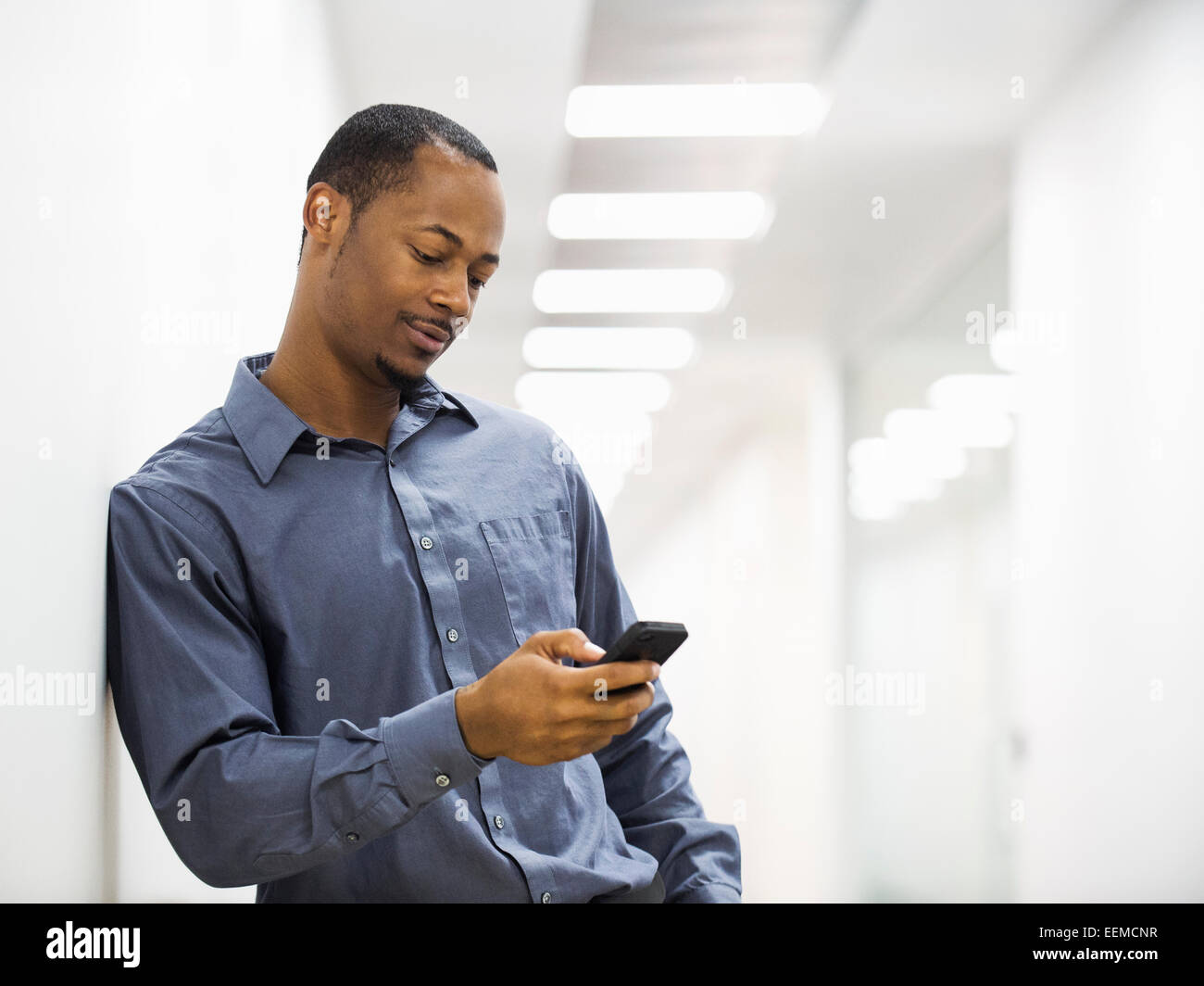 Schwarze Geschäftsmann mit Handy im Büro Korridor Stockfoto