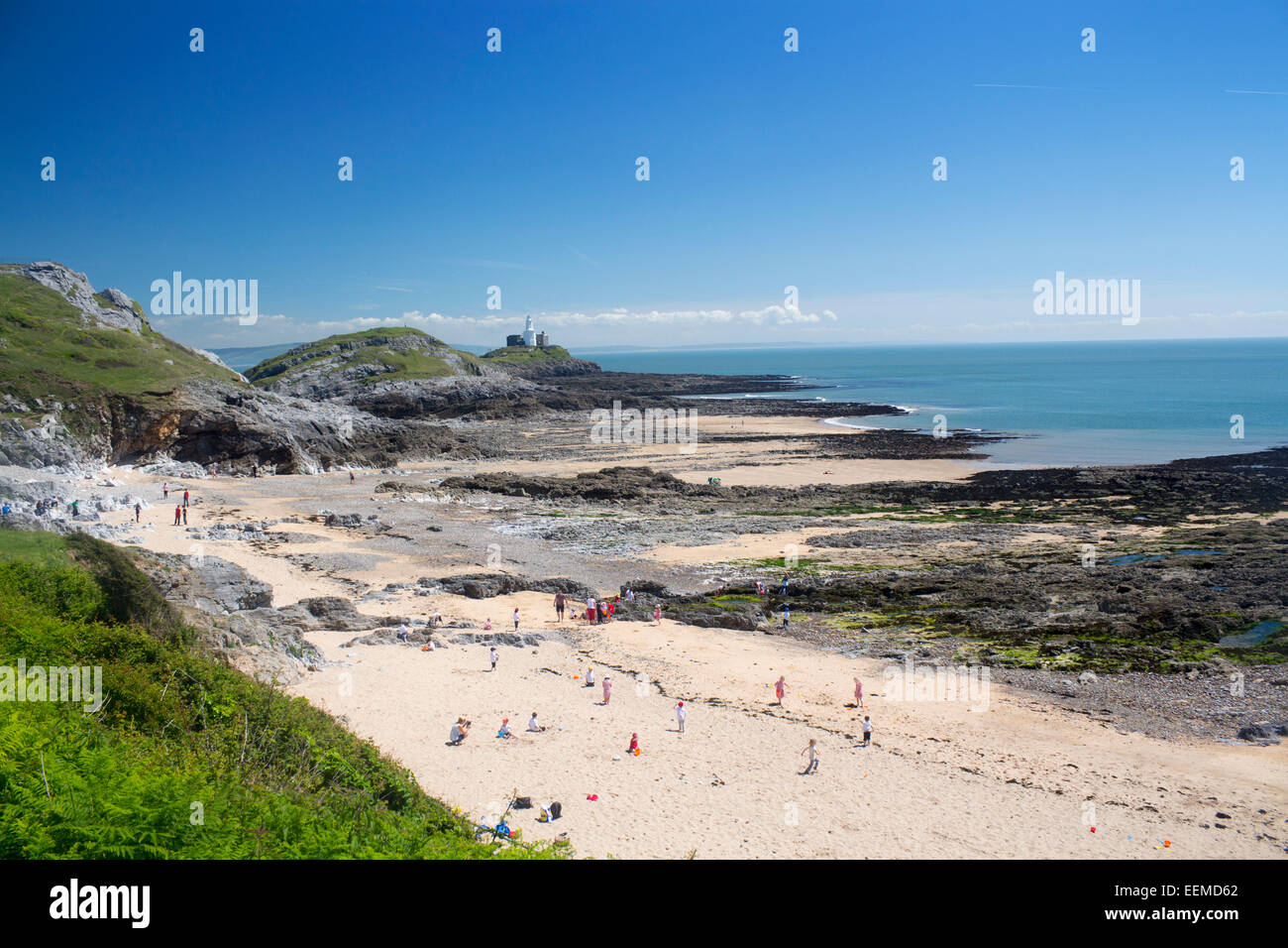 Armband-Bay Beach und Mumbles Head Leuchtturm mit Leuten am Strand bei Ebbe Swansea County Gower Halbinsel South Wales UK Stockfoto