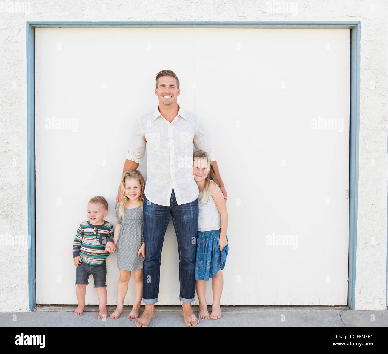 Kaukasische Vater und Kinder Lächeln in Einfahrt Stockfoto