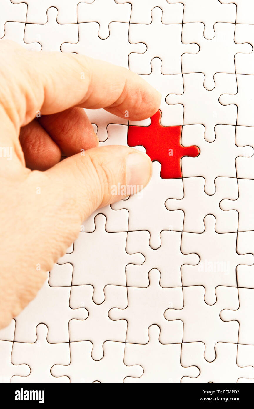 Hand des Menschen passend eine rote Puzzleteil um eine weiße Puzzle zu vervollständigen Stockfoto
