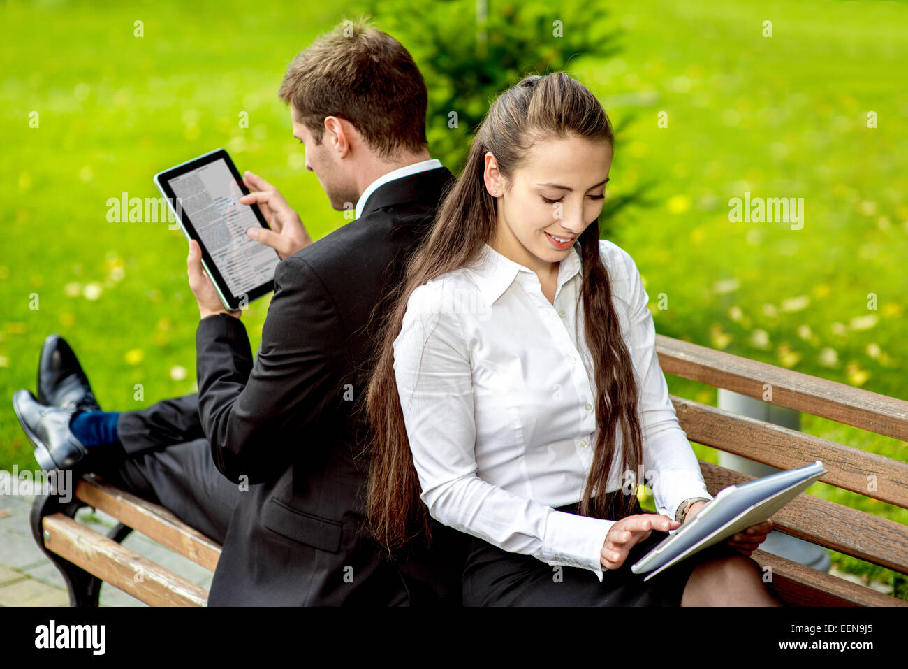 Young Business paar sitzt auf der Bank und lesen oder mit Tabletten im Freien arbeiten. Stockfoto