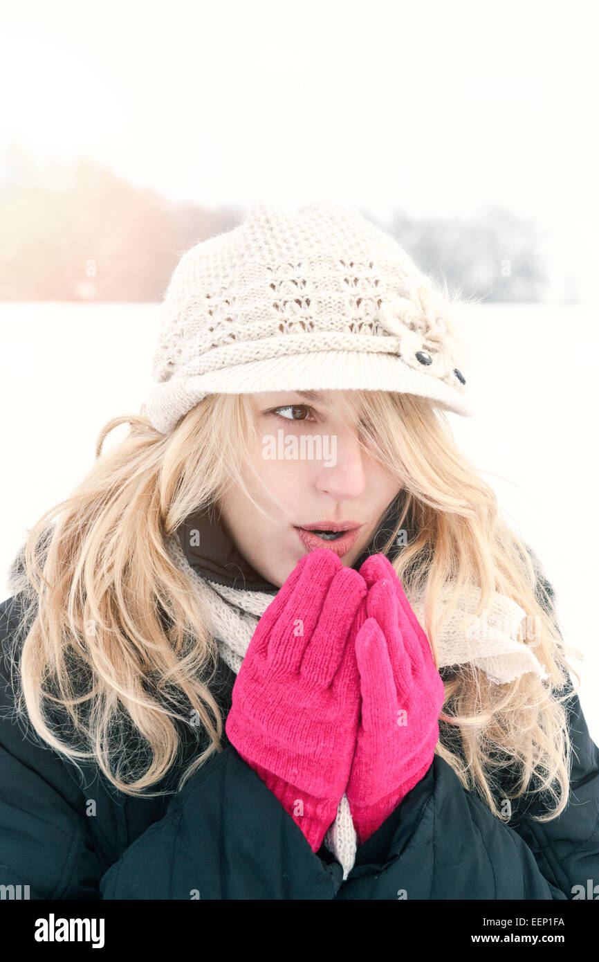 Winter-Frau im Schnee Foto, Schläge Atem ihre Hände außerhalb an kalten Wintertag. Porträt-kaukasischen weibliches Modell mit rosa Boxhandschuh Stockfoto