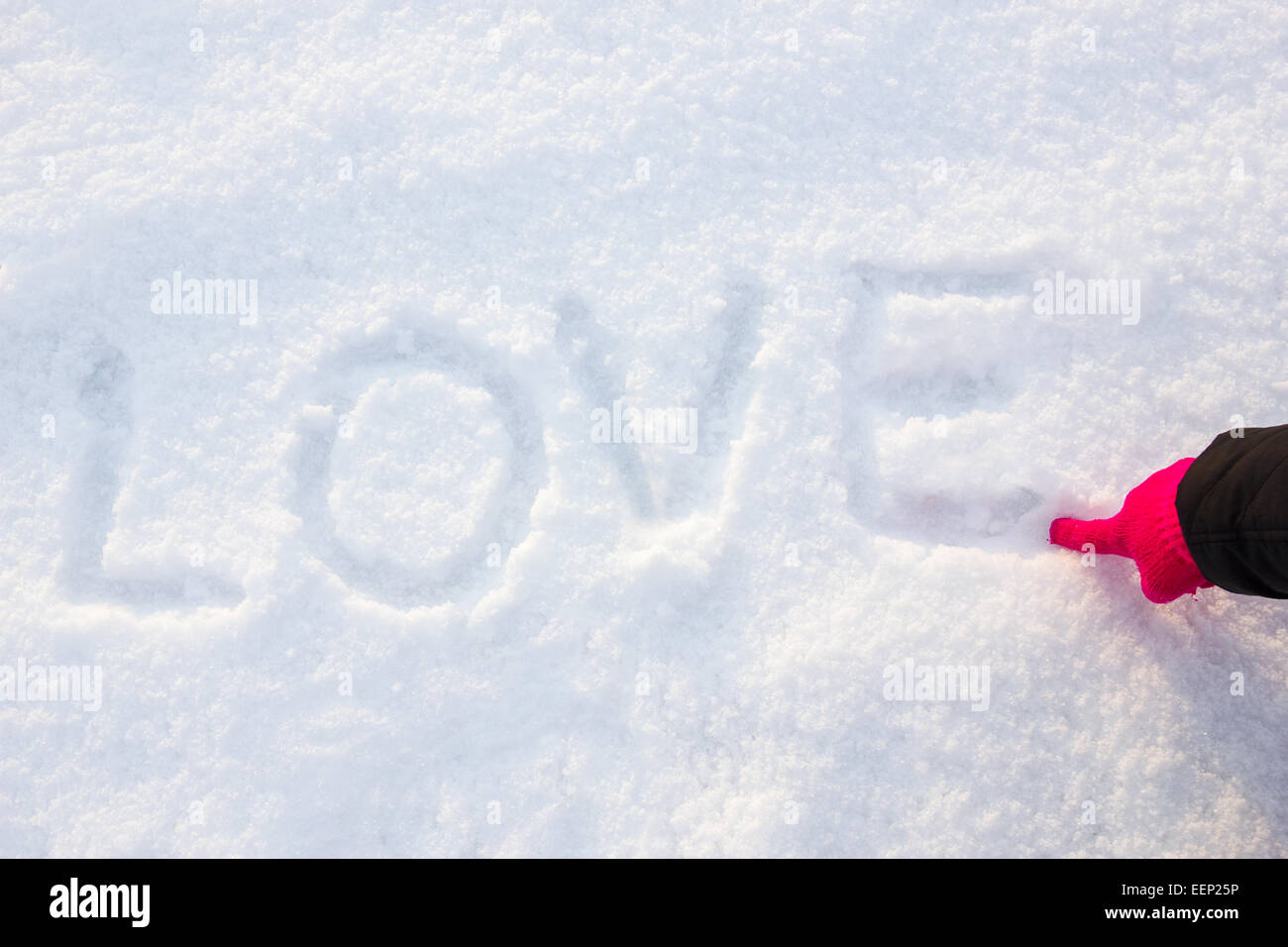 schriftliche oder per hand gezeichnet, in rosa Handschuh Wort Liebe auf weißen Schnee, romantische Bildkomposition. Menschliche Hand schreiben oder Zeichnen von Buchstaben Stockfoto
