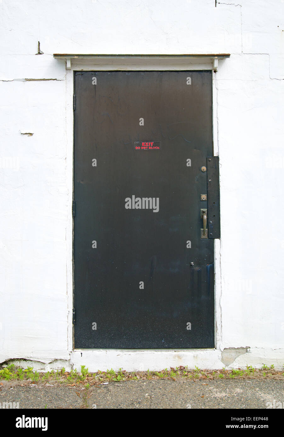 Eine äußere Stahl Ausgang Außentür in eine konkrete Stuck-Wand, die geknackt und verwittert ist montiert. Stockfoto
