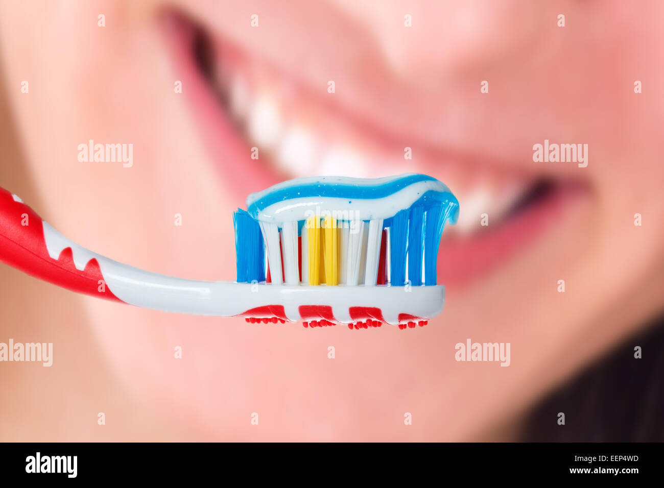 Roten Zahnbürste mit blauer Farbe zwei Zahnpasta mit menschlichen Lächeln Hintergrund. Foto von Dental-Hygiene und Gesunderhaltung Stockfoto
