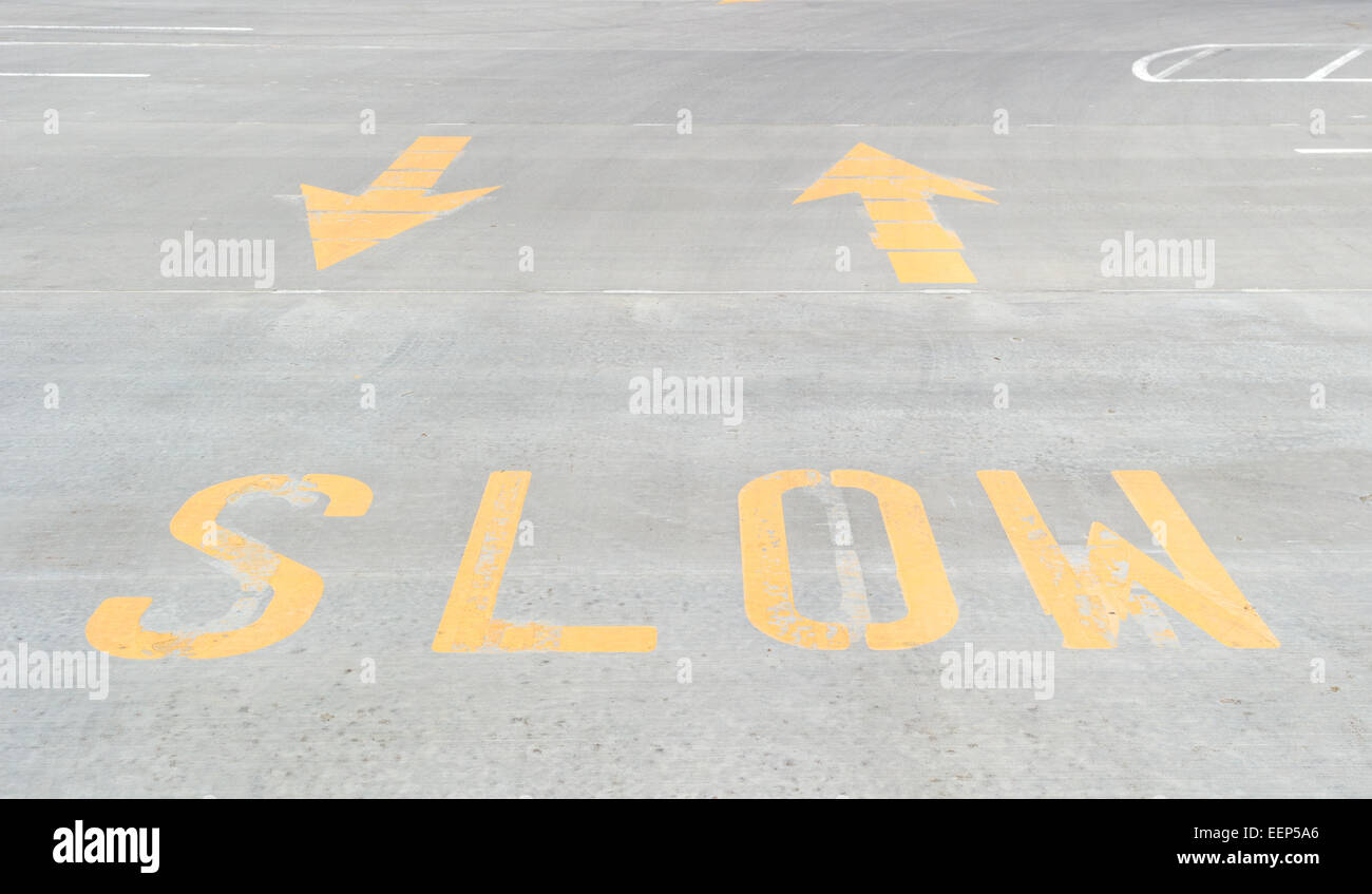 Ein helles Gelb langsamere Zeichen auf Beton mit Pfeile aufgedruckt. Stockfoto