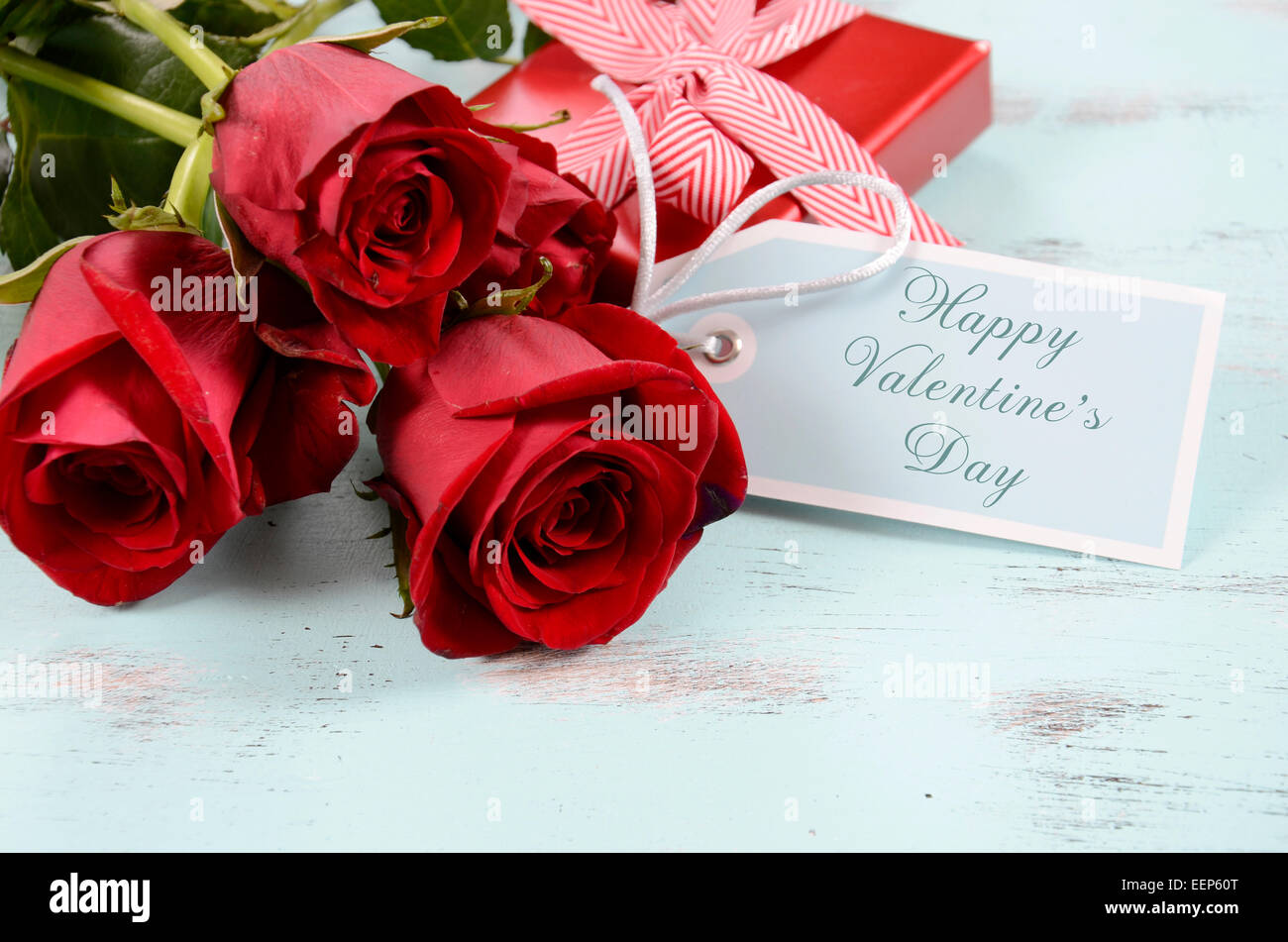 Vintage rote Rosen Geschenk für Valentinstag, Geburtstag oder besonderen Anlass auf blasse Aquablau recycelt notleidenden Holz Hintergrund, w Stockfoto