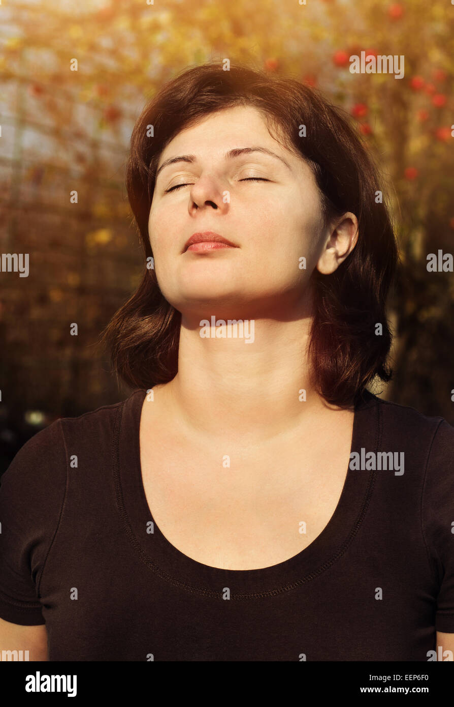Nahaufnahme Portrait der schönen Frau lächelt mit geschlossenen Augen über Sonneneinstrahlung, Meditation im freien Stockfoto