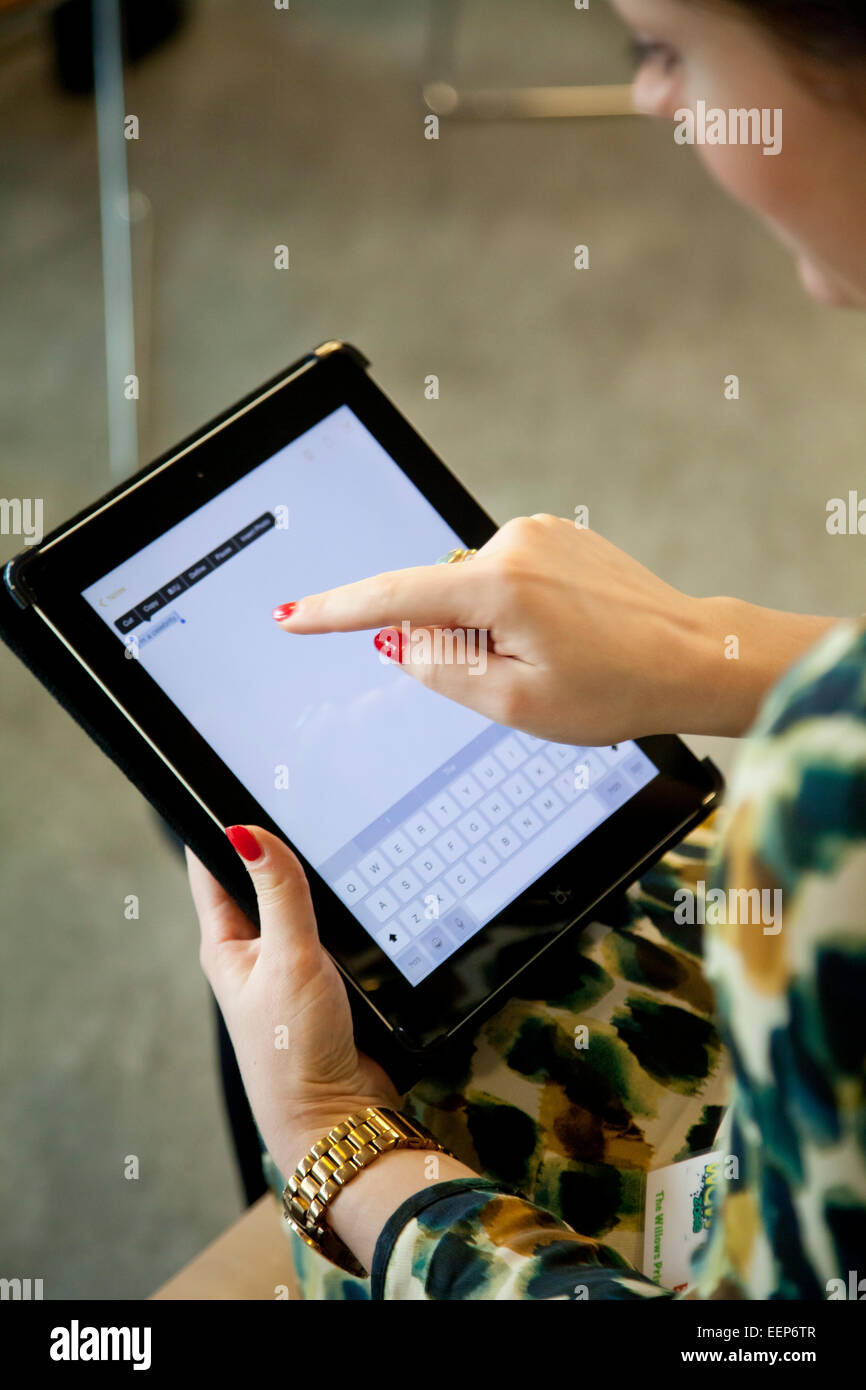 Frau mit roten Nägeln nutzt das iPad Stockfoto