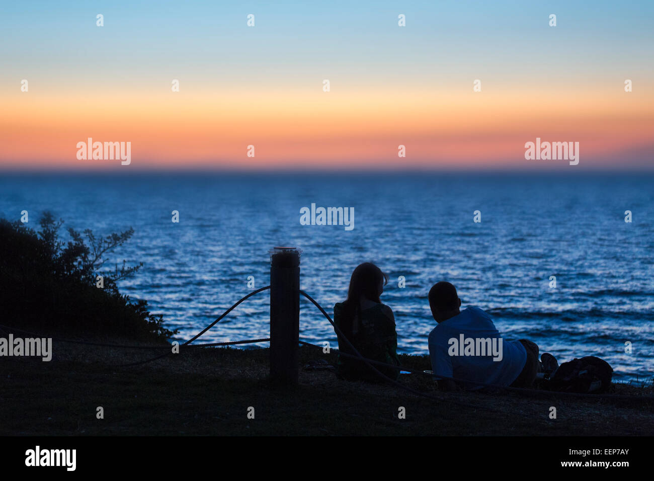 Romantisches Paar liegende Silhouette gegen Sonnenuntergang über der Bucht Stockfoto