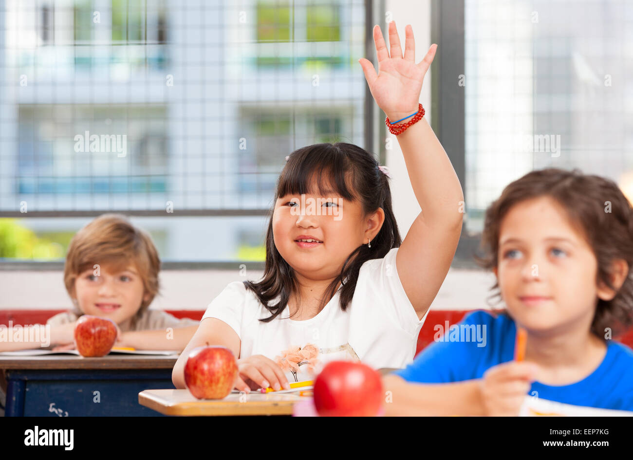 Asiatische Mädchen Hand in Multi-ethnischen elementare Klassenzimmer heben. Stockfoto