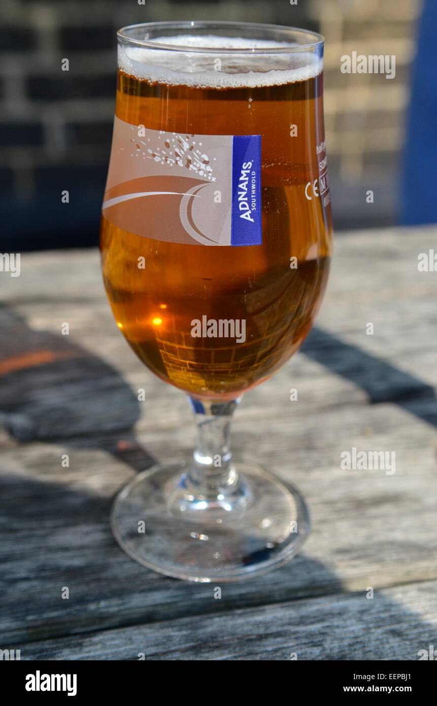 Glas der Adnams Bier auf dem Tisch außerhalb der Sohle Bay Inn in Southwold, Suffolk, England, UK Stockfoto