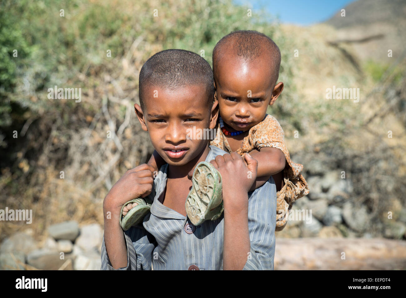 Zwei äthiopische einheimischen Kindern, junge mit Kopftuch tragen Baby auf ihr zurück in Äthiopien, Ostafrika Stockfoto