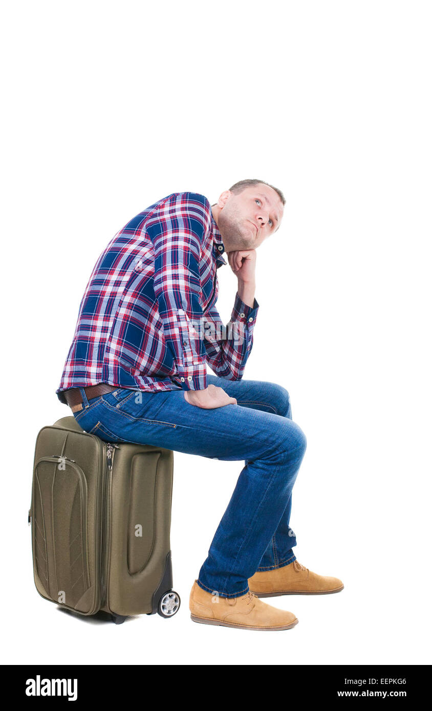 Rückansicht des ein Mann sitzt auf einem Koffer. am Bahnhof warten. Rückseite Blick auf Person.  Hintere Ansicht Menschen Sammlung. Stockfoto