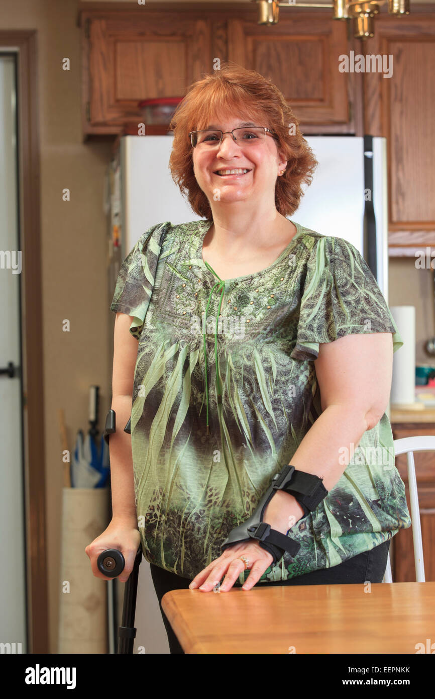 Frau mit RSD mit ihrer Hand Bandage und Krücke zu Hause Stockfoto