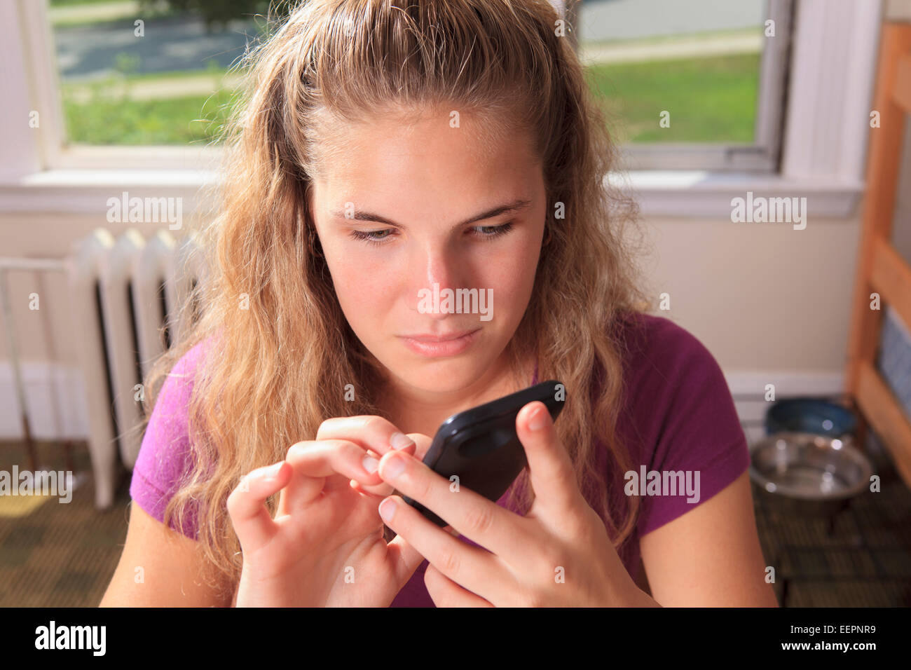 Schüler mit Sehbehinderung, die mit ihrem Handy in ihrem Zimmer im Studentenwohnheim Stockfoto