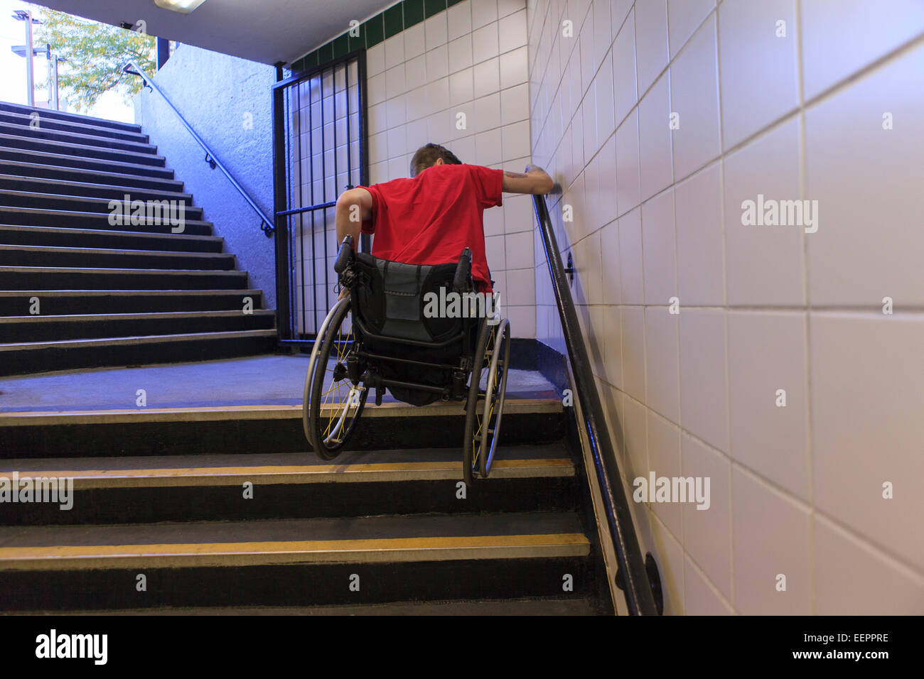 Trendige Mann mit einer Querschnittslähmung im Rollstuhl rückwärts u-Bahn Treppe hinunter Stockfoto