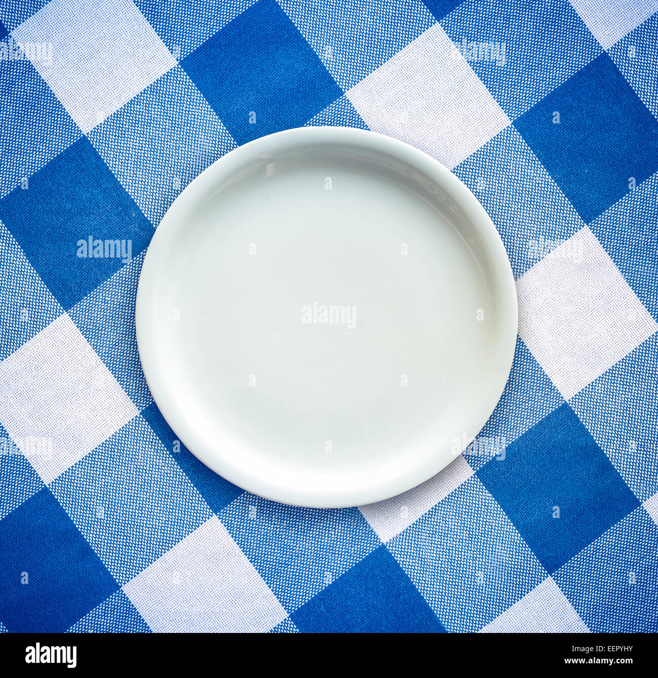 Leere weiße Platte auf einer aufgegebenen Tischdecke Stockfoto