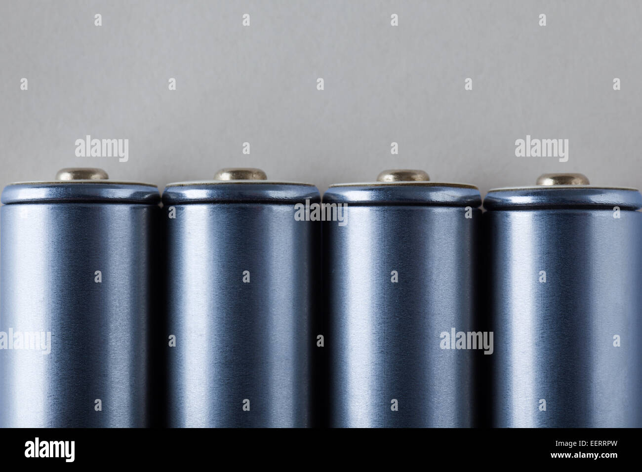 Vier AA blau Batterien auf grauem Hintergrund Stockfoto