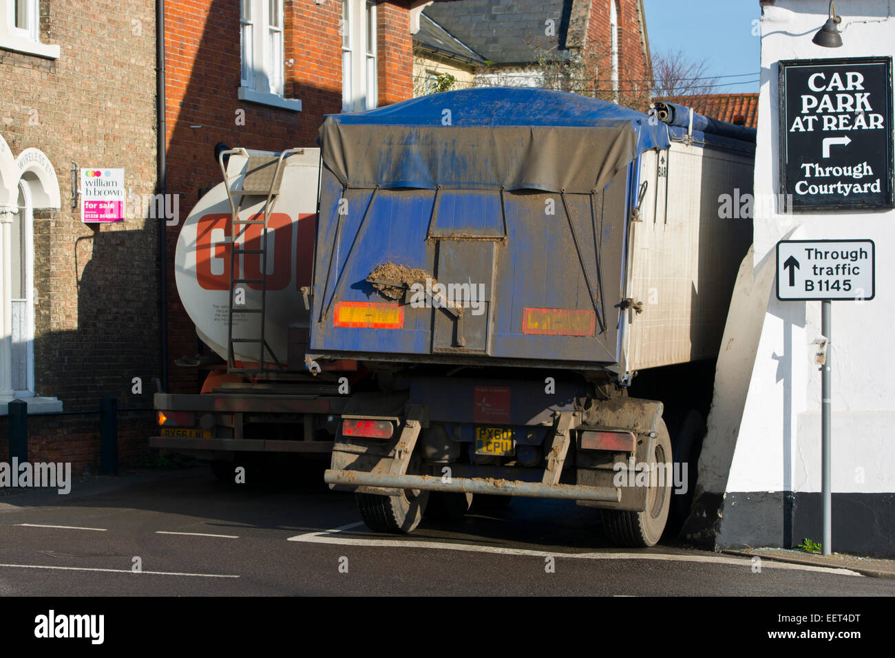 schwere Lkw LKWs quetschen sich durch ländliches Dorf Stockfoto