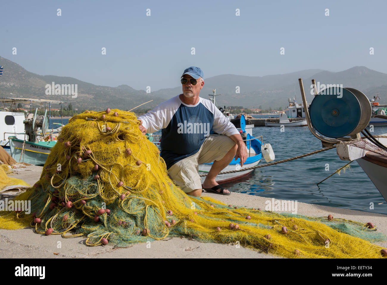 Reifer Mann auf ein Dock mit Fischernetzen, Griechenland Stockfoto