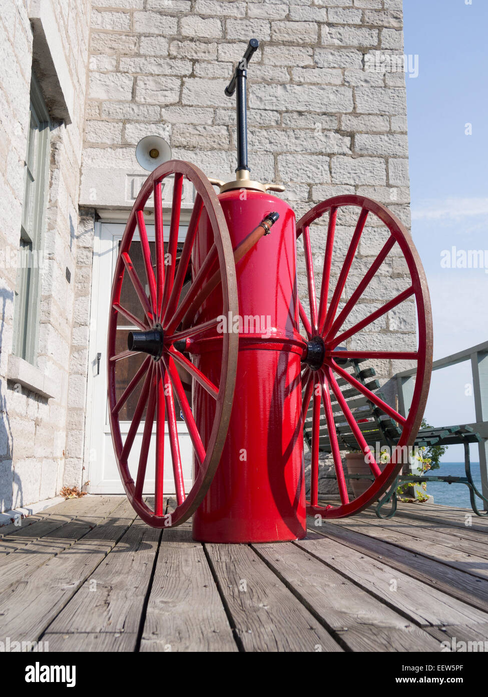 Antike Feuerlöschgeräte in rot. Antike Hand gepumpte Druckbehälter auf Rädern für die Brandbekämpfung auf der Veranda Stockfoto