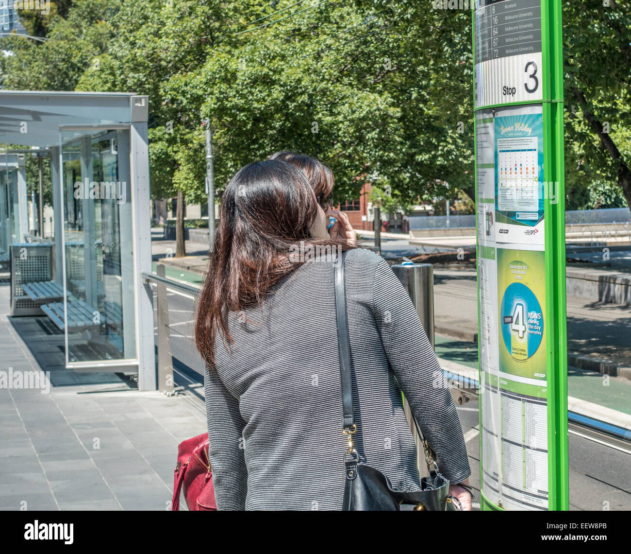 Zwei Mädchen auf der Suche im Tram/Zug Fahrplan tram stop in Swanston Street, Melbourne, Australien Stockfoto