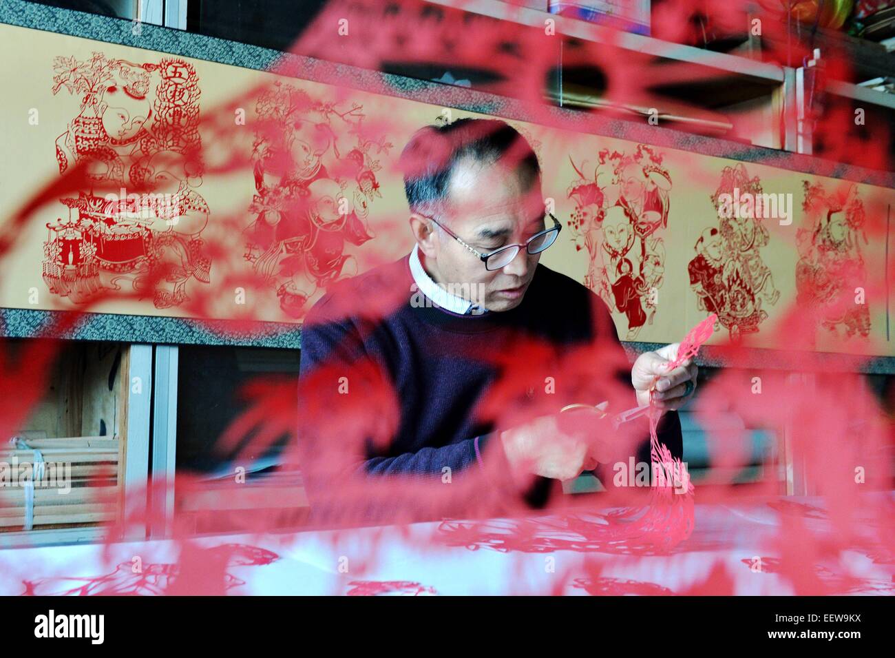 Hejian, Chinas Provinz Hebei. 21. Januar 2015. Volkskünstler Song Baoshu macht Papierschnitten in Hejian Stadt, Nordchinas Provinz Hebei, 21. Januar 2015. Mit einem paar der Schere und etwas Papier können chinesische Handwerker Papierschnitten mit komplizierten Mustern und Bildern erstellen. Als Papierschnitt im Blut läuft, widmet der 61 Jahre alte Lied Baoshu sich bewahren. © Zhu Xudong/Xinhua/Alamy Live-Nachrichten Stockfoto