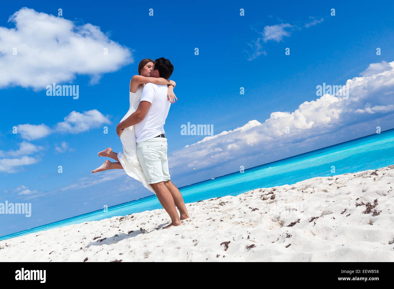 Glückliche Brautpaar in weißen Kleidern, die Spaß am Strand mit Turquose Meer Hintergrund Stockfoto