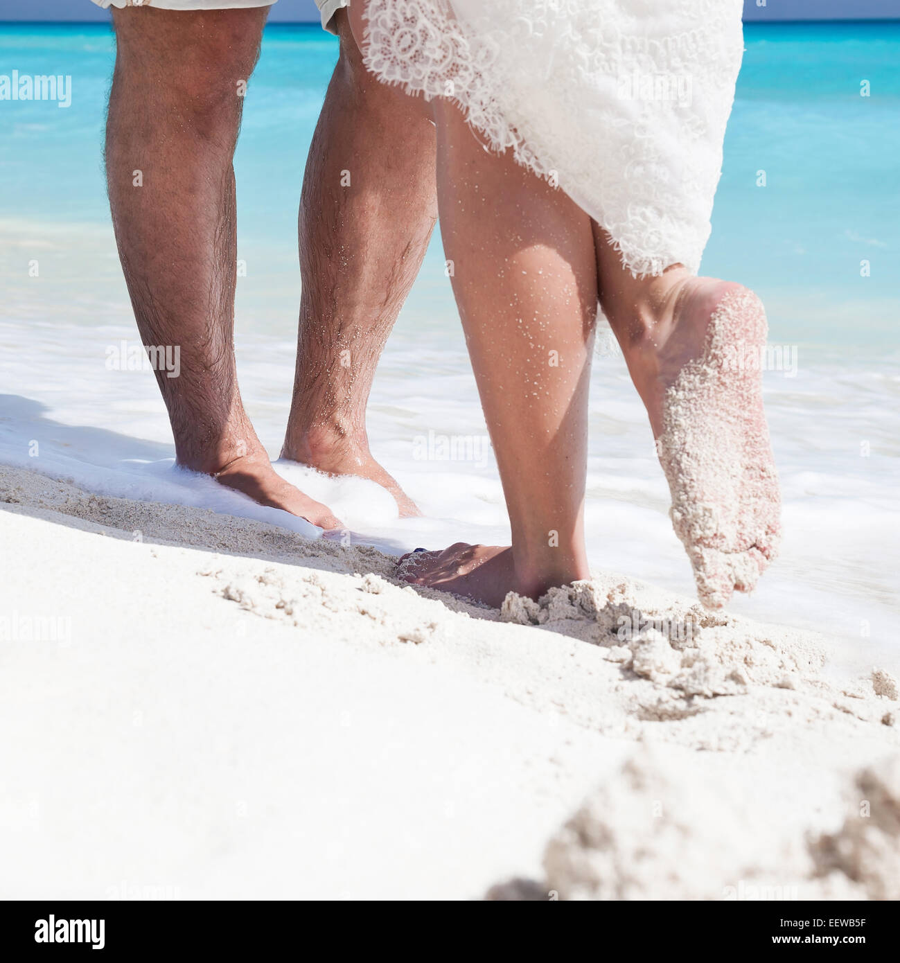 Männliche und weibliche Füße auf weißem Sand, küssen Nahaufnahme Stockfoto