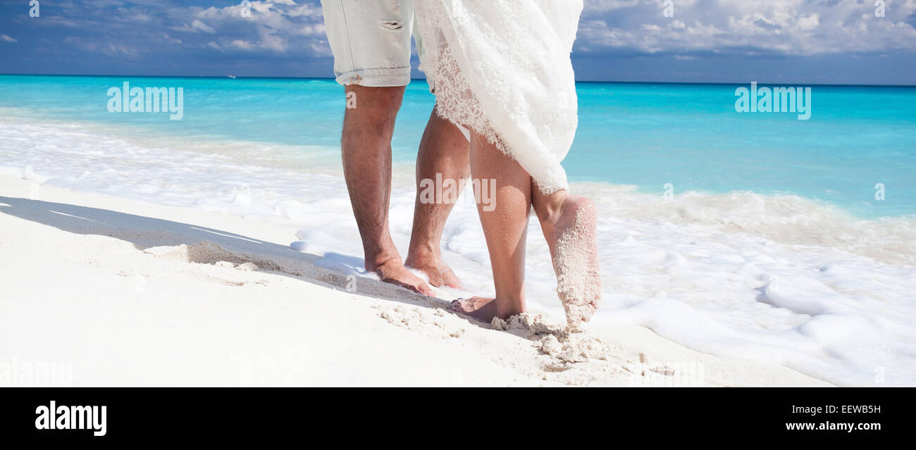 Männliche und weibliche Füße auf weißem Sand, küssen Nahaufnahme Stockfoto