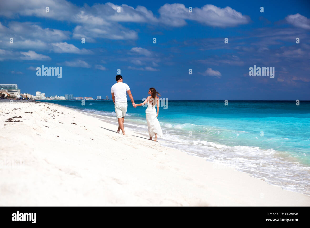 Junge schöne Brautpaar in Liebe Hand in Hand und Fuß am tropischen Sandstrand, Ansicht von hinten Stockfoto