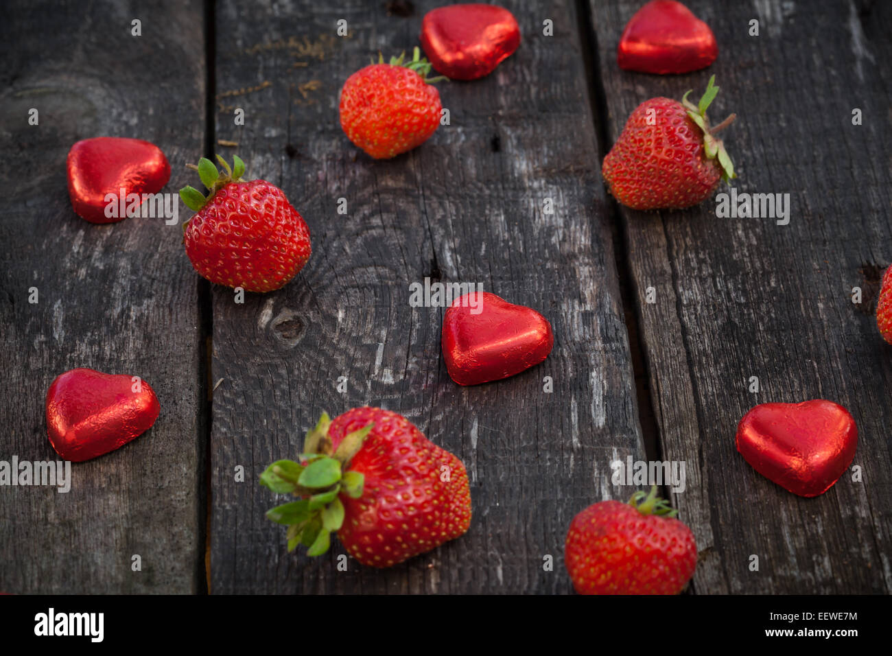 Frische rote Erdbeeren und Schokolade Herz Candy auf alten Holztisch Stockfoto