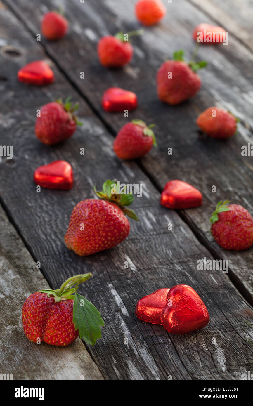 Frische rote Erdbeeren und Schokolade Herz Candy auf alten Holztisch Stockfoto