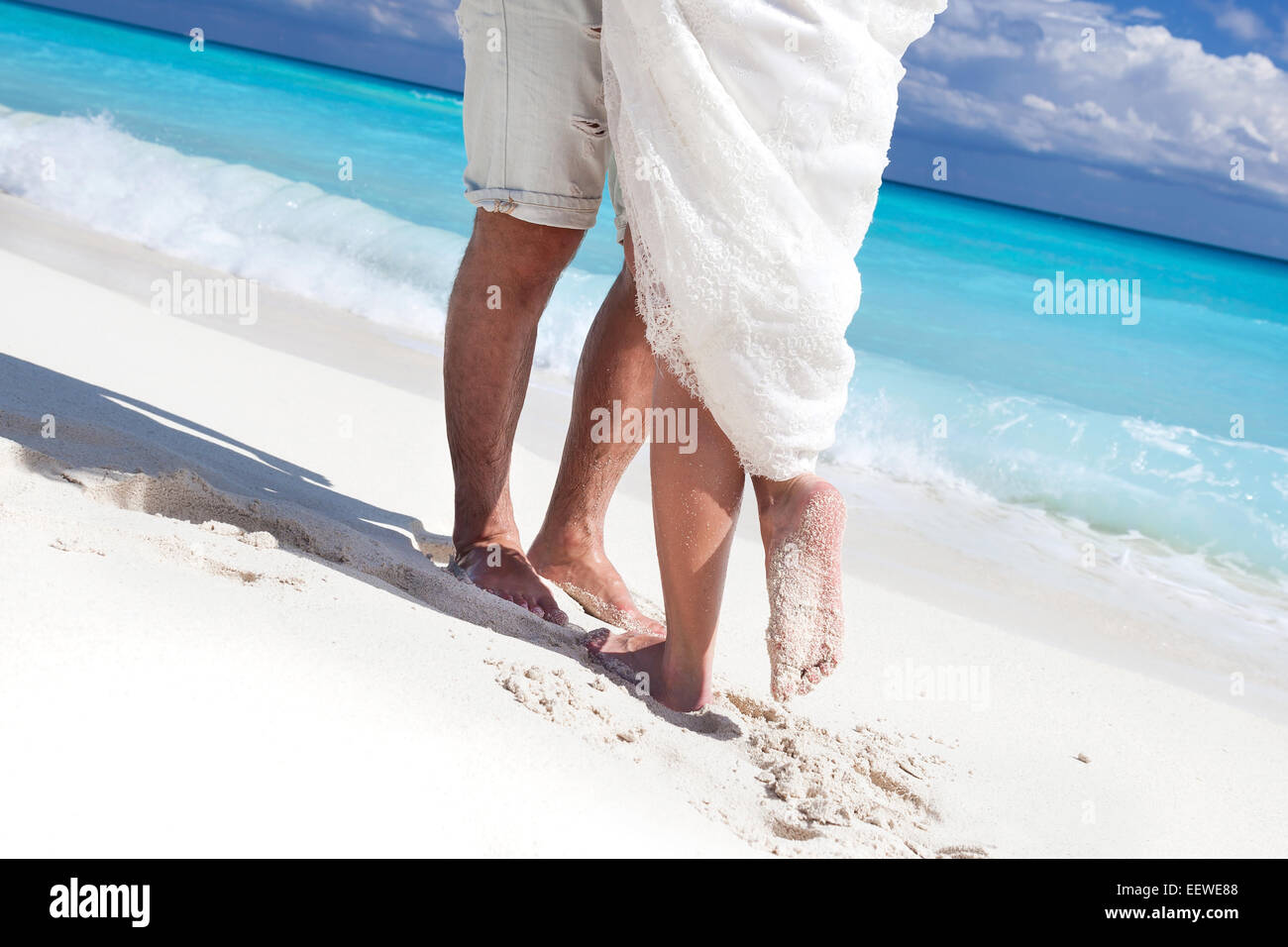 Männliche und weibliche Füße auf weißem Sand, küssen Nahaufnahme Stockfoto