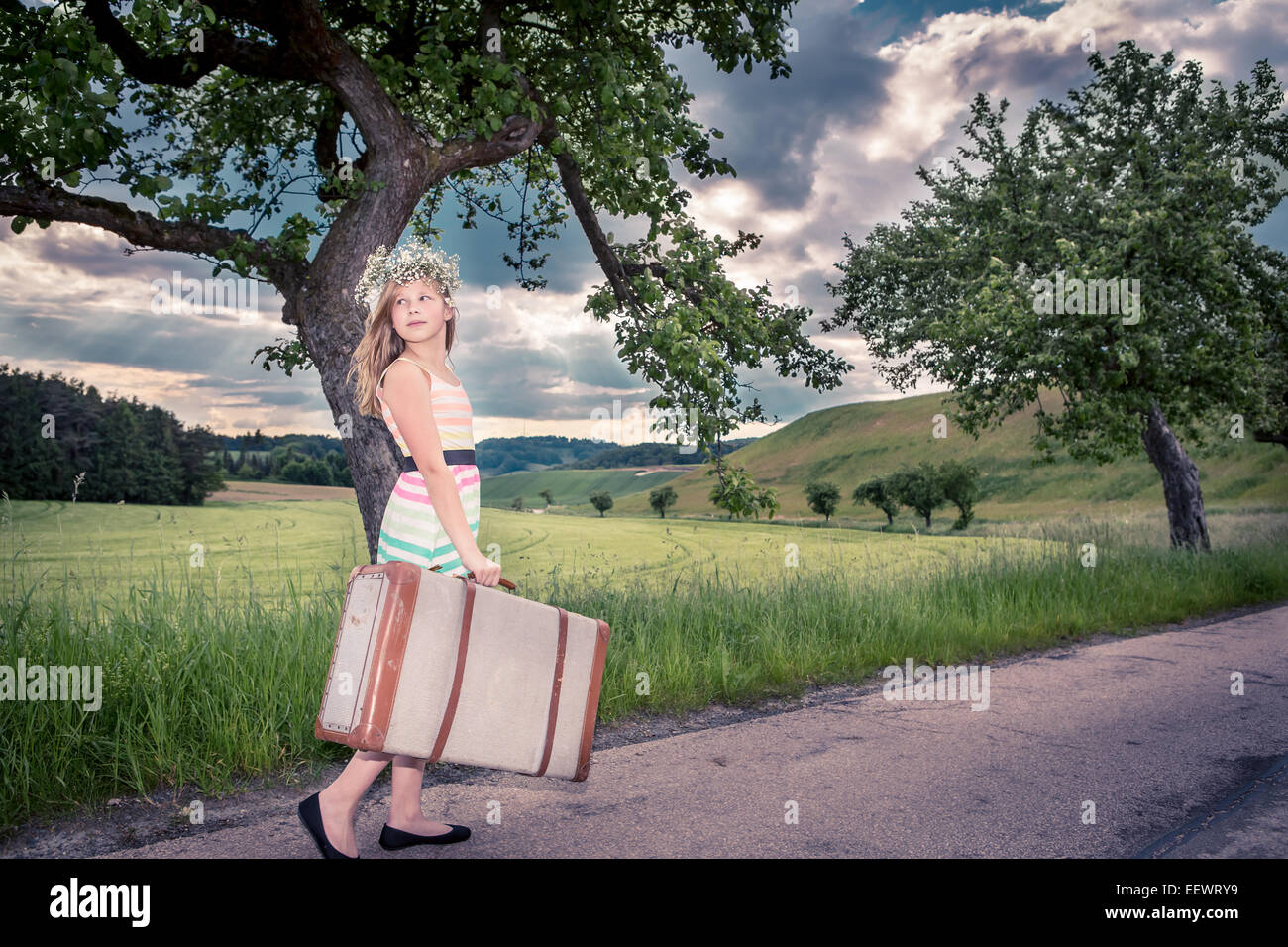 Mädchen im Teenageralter auf Landstraße mit einem Koffer Stockfoto