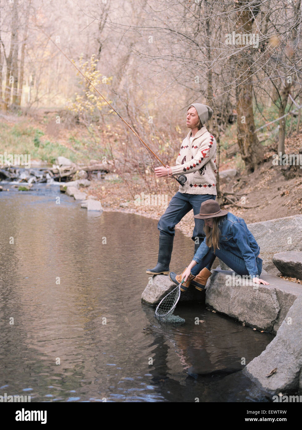 Junges Paar in einem Wald, in einem Fluss angeln. Stockfoto
