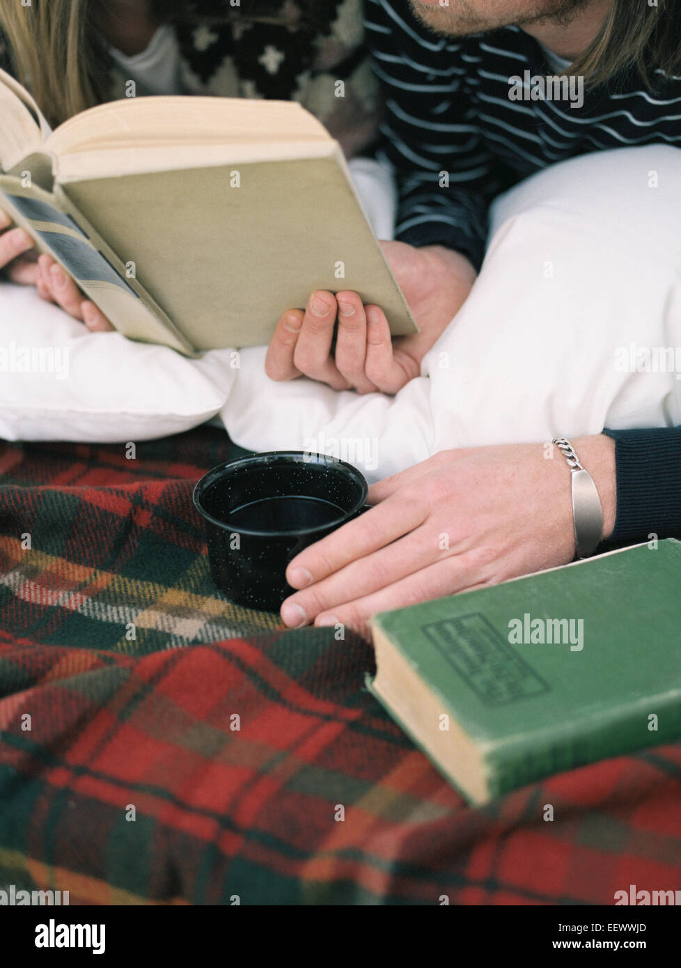 Der junge Mann ein Buch lesen, hält einen Becher hautnah. Stockfoto